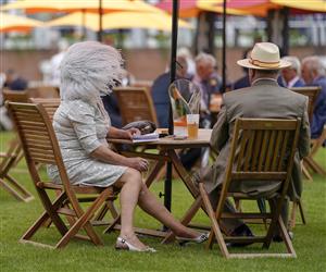 CHICHESTER, ENGLAND - JULY 27: A strong breeze blows through a lady's hat on the Champagne lawn during the Qatar Goodwood Festival at Goodwood Racecourse on July 27, 2021 in Chichester, England. (Photo by Alan Crowhurst/Getty Images)